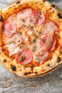 İtalyan usulü dört etli pizza, salam, pastırma ve jambon masanın üzerinde tahtaya yakın plan. Yukarıdan dikey üst görünüm