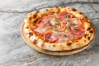 Masanın üzerinde jambonlu, jambonlu, jambonlu ve jambonlu yanmış et pizzası. Yatay