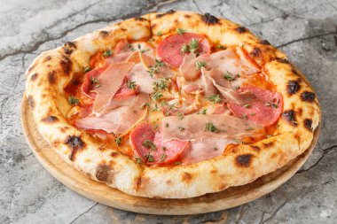 Prosciutto, salam, pastırma ve jambonlu nefis otantik et pizzası masanın üzerinde tahtaya yakın plan. Yatay