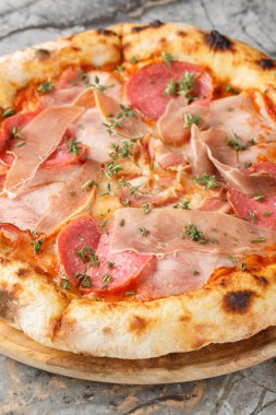 Napoli usulü etli pizza. Masadaki tahta tahtaya yakın plan salam otları. Dikey