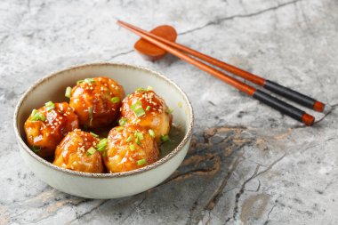 Chinese Tiger Skin Eggs or Hu Pi Dan, a delicious crispy dish with spicy sauce, green onions and sesame seeds, close-up in a bowl on a table. Horizonta