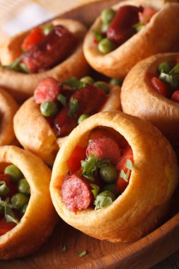 Yorkshire pudding with sausage and green peas macro. vertical