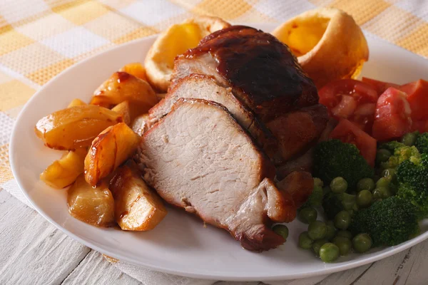 Baked pork with potatoes, fresh vegetables and Yorkshire pudding — Stock Photo, Image