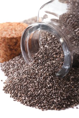 Useful Chia seeds spill out of a glass jar macro isolated on whi