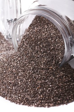Chia seeds spill out of a glass jar macro isolated on white. ver