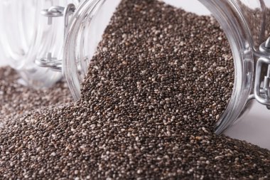 Chia seeds macro spill out of glass jar. Horizontal