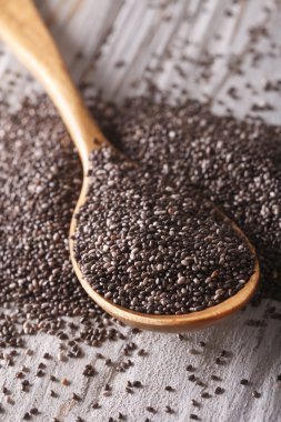 Chia seeds in a wooden spoon on the table close-up. vertical