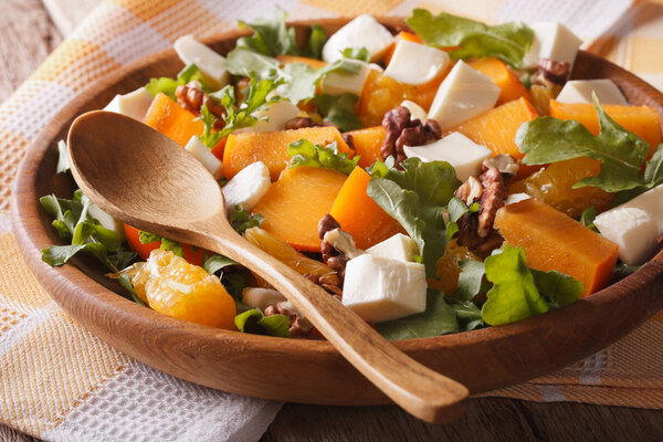 Fresh salad with persimmons, walnuts, arugula, cheese close-up.