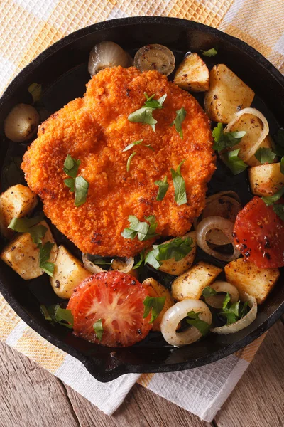 Weiner schnitzel, fried potatoes in a pan closeup. vertical top — Stock Photo, Image