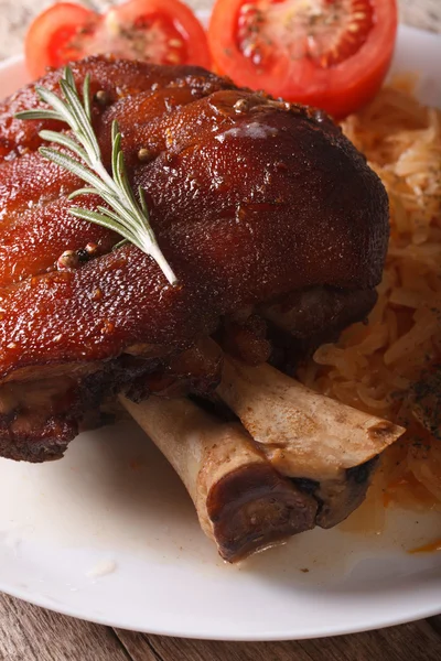Canela de porco cozida no forno e chucrute em uma macro de chapa. vertical — Fotografia de Stock