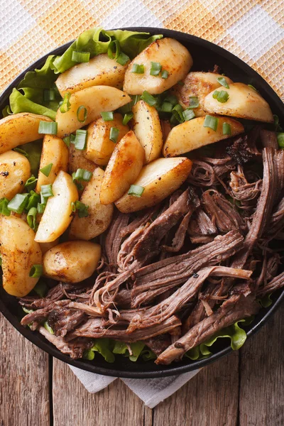 Kihúzta a sertéshús és a sült krumpli közelről egy tányérra. függőleges top — Stock Fotó