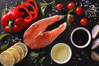 Çiğ somon ve malzemelerin üzerine bir kara tahta yakın çekim. Yatay