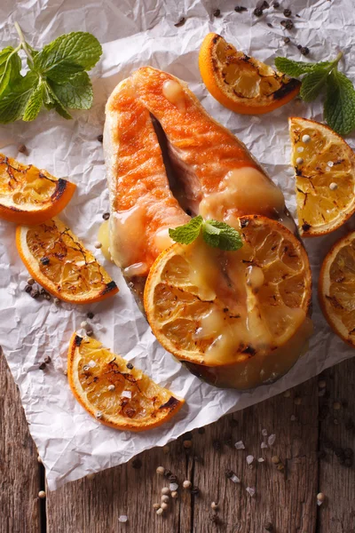 Salmón al horno con naranjas primer plano sobre papel de hornear. plano vertical —  Fotos de Stock