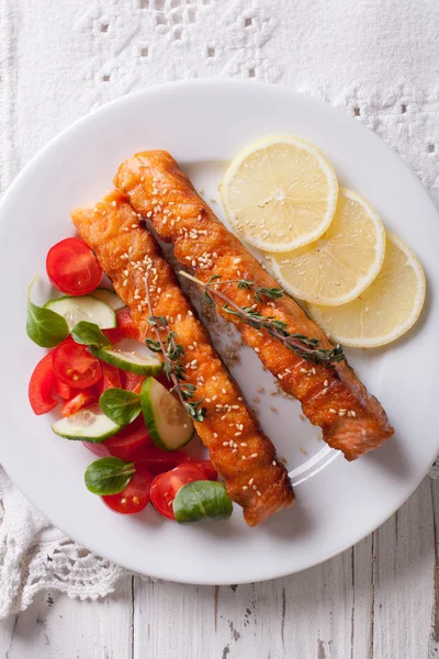 Salmão grelhado com limão e salada em um prato close-up. vertica — Fotografia de Stock