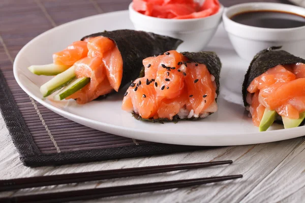 Temaki lax sushi med sojasås och syltad ingefära på nära håll. — Stockfoto