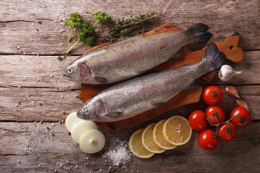raw rainbow trout with ingredients on a table. Horizontal top vi clipart