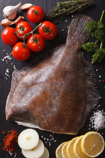 Сырая камбала с ингредиентами на доске с шифер крупным планом. Вертикаль
