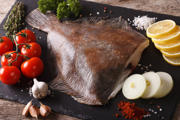Сырая камбала с ингредиентами на доске с шифер крупным планом. Горизонт
