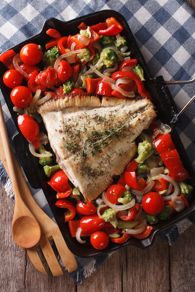 камбала с овощами крупным планом на сковороде. Вертикальный верх
 