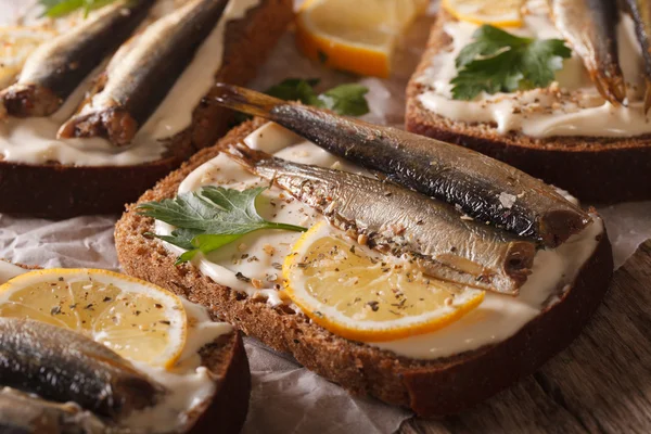 Fish sandwiches with sprats, cream cheese and lemon macro. horiz — Stock Photo, Image