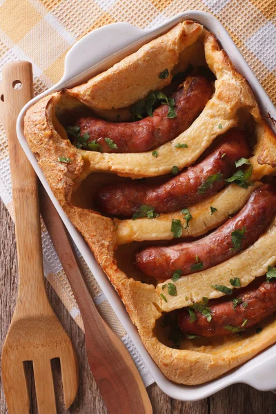 English toad in the hole into a baking dish close up. Vertical t — Stock Photo, Image