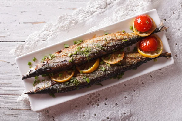 Saury grilled with vegetables on a plate close-up. Horizontal to — Stock Photo, Image