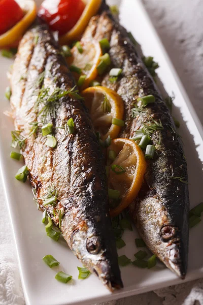 Tasty grilled saury with lemon on a plate close-up. vertical — Stock Photo, Image