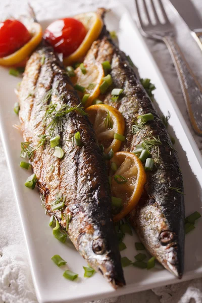 Fish saury grilled with lemon and chives on a plate close-up. ve — Stock Photo, Image