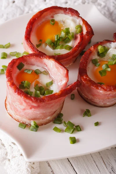 Fried eggs wrapped in bacon on a plate close-up. vertical — Stock Photo, Image