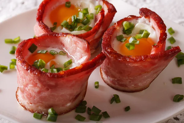 Fried eggs wrapped in crispy bacon on a plate close-up. horizont — Stock Photo, Image