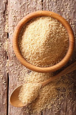 Ahşap kase ve kaşık yakın çekim ham kuskus. Dikey üst v