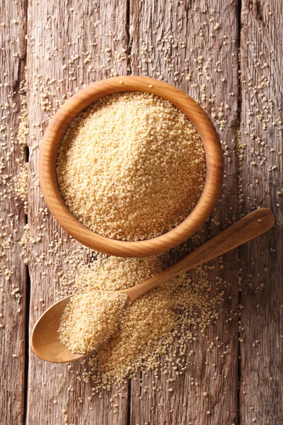 Raw Couscous in a wooden bowl and spoon. vertical top view — Stock Photo, Image