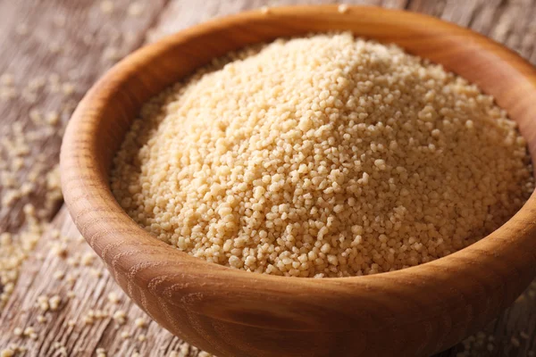 Raw couscous in a wooden bowl on a table close-up. horizontal — Stock Photo, Image
