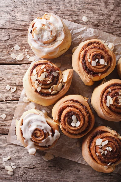 Glazed Cinnamon rolls with almond close up. vertical top view — Stock Photo, Image