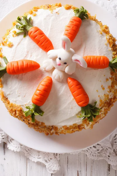 Carrot cake with candy bunny close-up on the table. vertical top — Stock Photo, Image