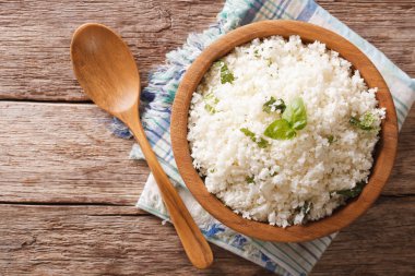 Cauliflower rice with basil in a bowl close-up. Horizontal top v clipart