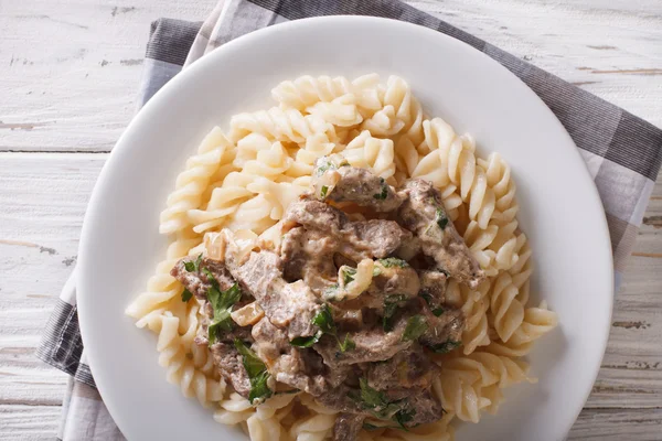 Boeuf Stroganow i makaron fusilli zbliżenie na talerz. pozio — Zdjęcie stockowe