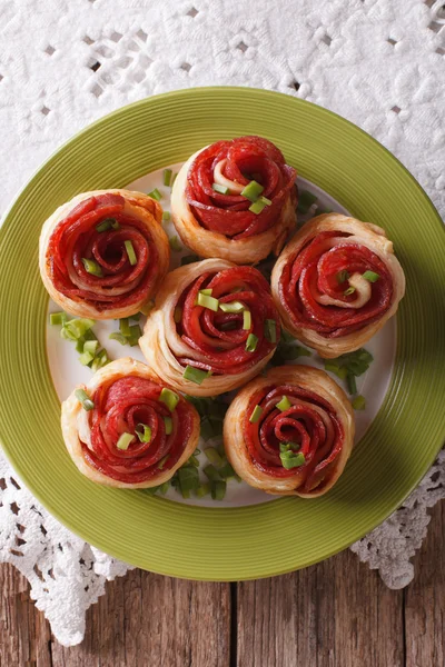 Baked rolls with salami in the form of roses close-up. Vertical