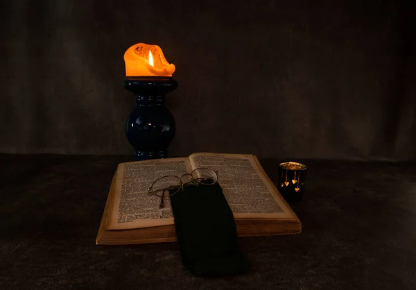 Burning candle and an open old book — Stock Photo, Image