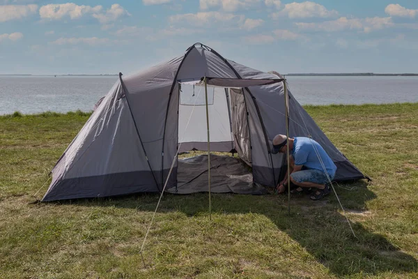 Man setting up a tent at the waterline — Stock Photo, Image