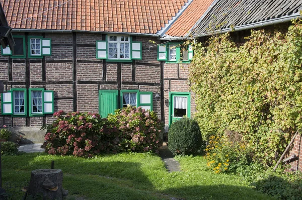 Fazenda com jardim e casa velha persianas verdes e flores — Fotografia de Stock