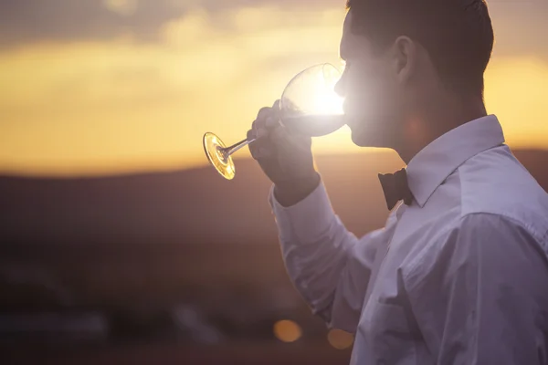 Elegante jovem bebendo vinho ao pôr do sol — Fotografia de Stock