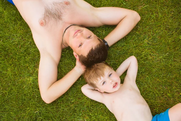 Padre con hijo acostado en la hierba — Foto de Stock