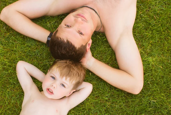 Pai com filho deitado na grama — Fotografia de Stock