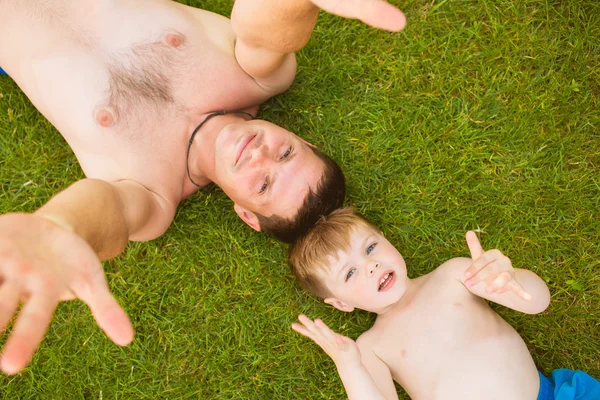 Pai com filho deitado na grama — Fotografia de Stock