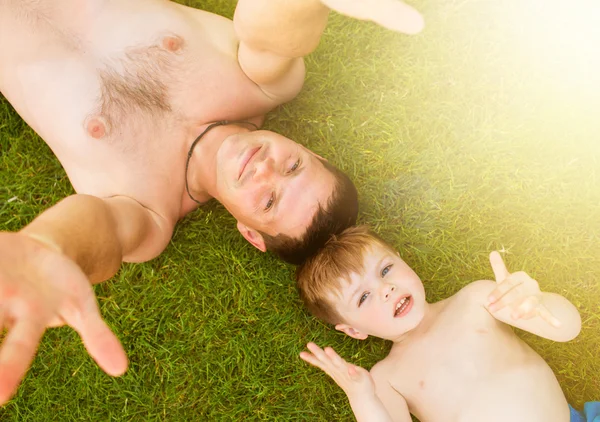 Padre con hijo acostado en la hierba — Foto de Stock