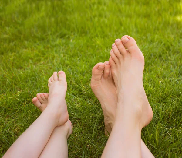 Закройте женские и детские ноги, лежащие на траве . — стоковое фото
