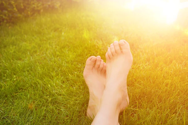 Zblízka ženské nohy leží na trávě. — Stock fotografie