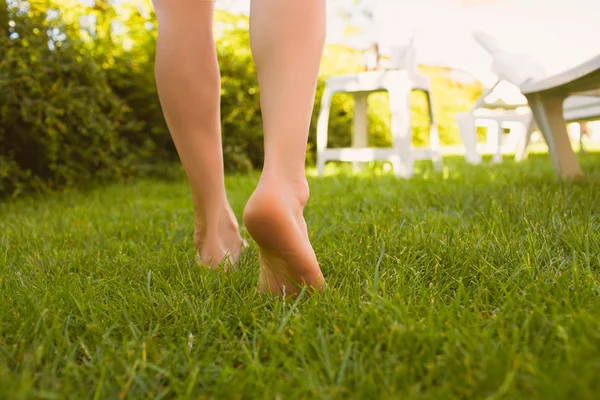 Close up female legs walking on the grass.