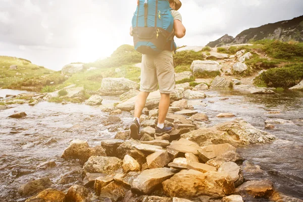 Hiker man with backpack crossing a river. — Stock Photo, Image